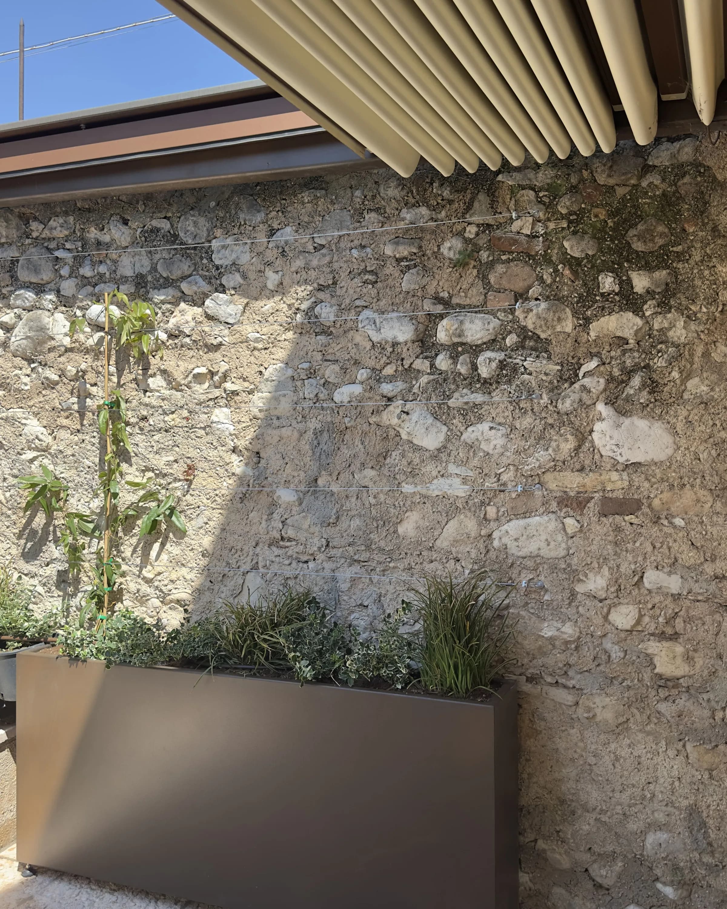 Vista d'insieme del portico con pergola corten e fioriera in metallo