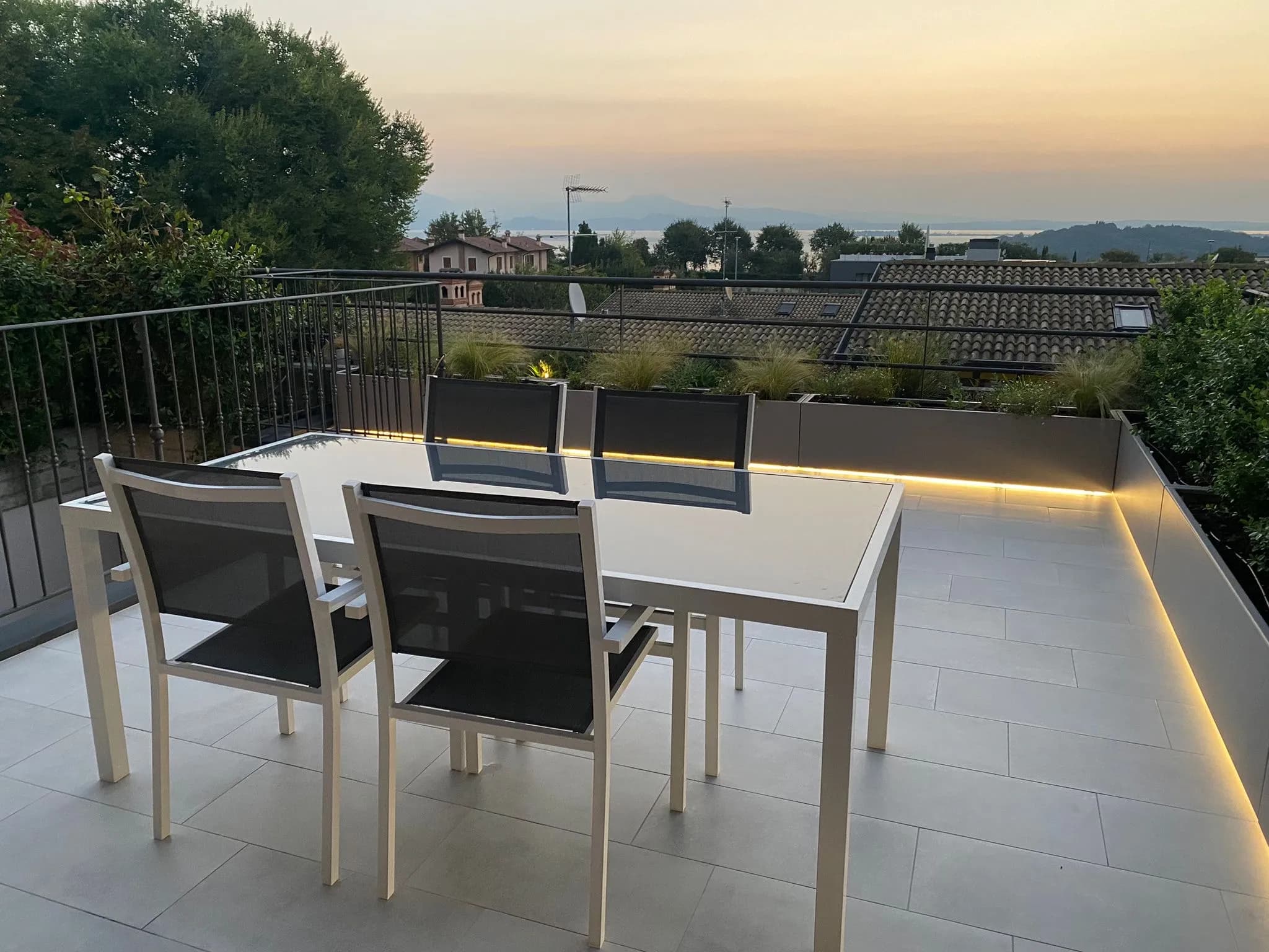 realizzazione terrazzo, tavolo da pranzo, illuminazione LED, fioriere in metallo